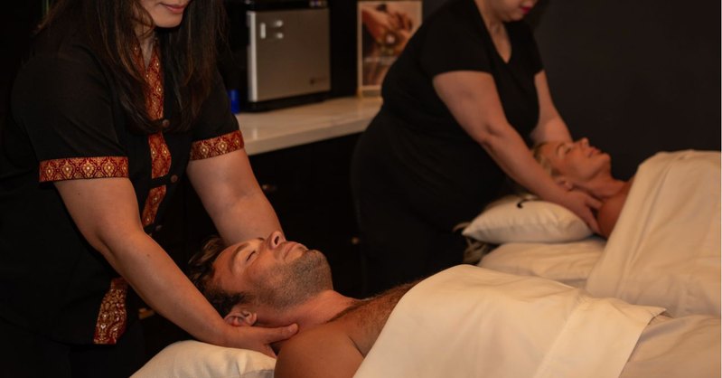 Two therapists giving a side-by-side couples massage